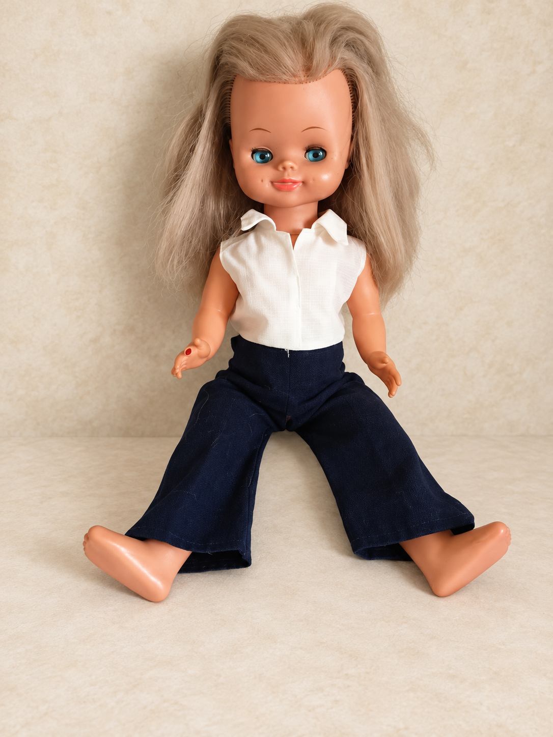 « Delphine », poupée Bella — collection de Sylvie — La Bella de Sylvie, appelée Delphine par sa propriétaire, aux longs cheveux blonds et aux yeux bleus, portant sa tenue d’origine : chemisier blanc sans manches et pantalon bleu marine évasé, assise pieds nus — vue 1.