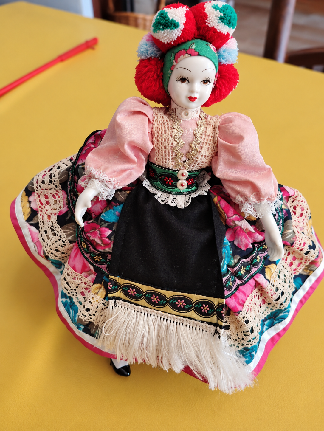 Poupée folklorique et souvenir de Tihany — Vue d’ensemble : visage peint, manches roses, jupe fleurie et coiffe à pompons — vue 1.